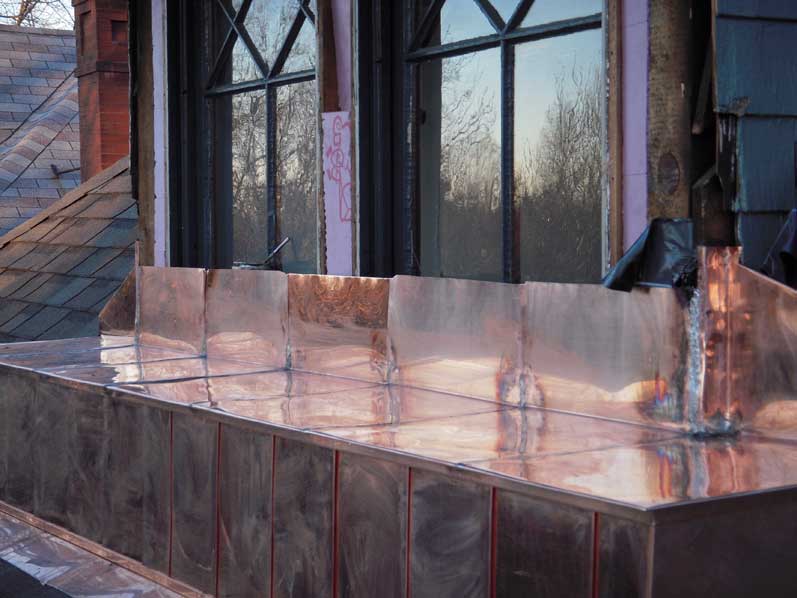 Gleaming copper standing seam roof panels catching golden light